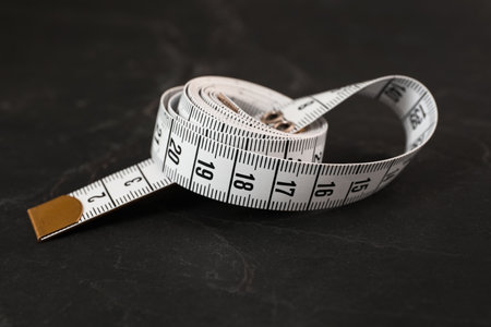 White measuring tape on black slate table, closeup