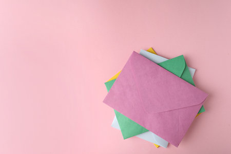 Colorful paper envelopes on pink background, flat lay. Space for textの写真素材