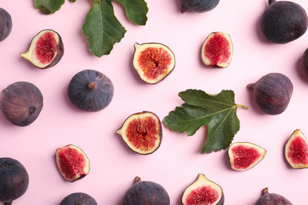 Delicious ripe figs and green leaves on pink background, flat layの写真素材
