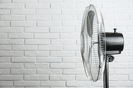 Electric fan near white brick wall, space for text. summer heatの写真素材
