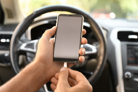 Man connecting charging cable to smartphone in car, closeup