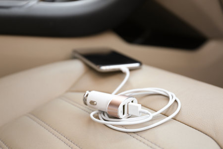 Adapter with connected charging cable and mobile phone in car, closeupの写真素材