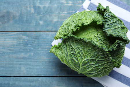 Fresh ripe savoy cabbage on blue wooden table, top view. Space for text