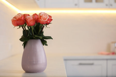 Vase with beautiful roses on countertop in kitchen, space for text. interior designの写真素材