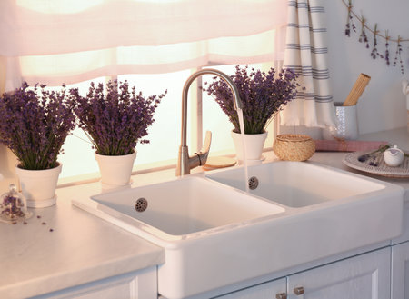 Beautiful lavender flowers on countertop near sink in kitchenの写真素材
