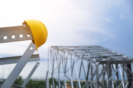 High voltage tower construction with yellow hard hat outdoors. Installation of electrical substationの写真素材