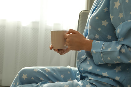 Woman in pajamas with cup at home, closeupの写真素材