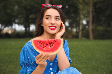 Beautiful young woman with watermelon in park on sunny dayの写真素材