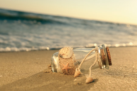 Wedding invitation in glass bottle on sandy beach at sunsetの写真素材