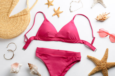 Beautiful pink bikini and beach accessories on white background, flat layの写真素材