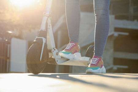 Woman riding electric kick scooter outdoors, closeup