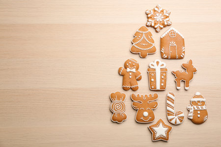 Christmas tree shape made of delicious gingerbread cookies on wooden table, flat lay. Space for text