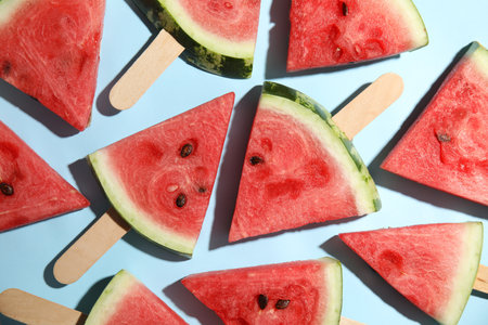 Slices of ripe watermelon on light blue background, flat layの写真素材