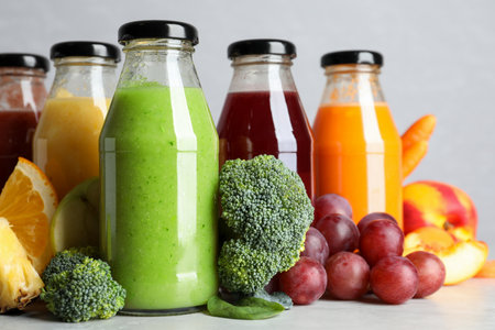 Bottles of delicious juices and fresh fruits on marble tableの写真素材