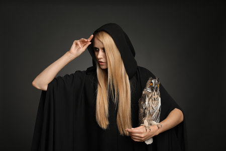 Witch in black mantle with owl on dark background. scary fantasy characterの写真素材