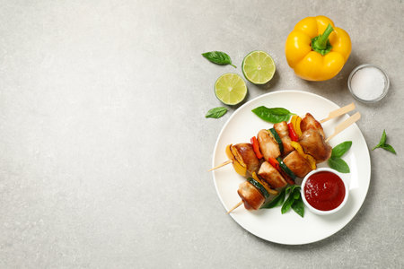 Delicious chicken shish kebabs with vegetables and ketchup on gray table, flat lay. Space for textの写真素材