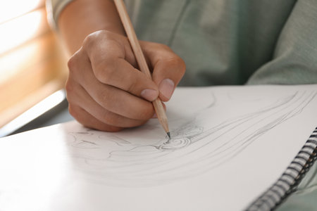 Man drawing portrait with pencil in notepad indoors, closeupの写真素材