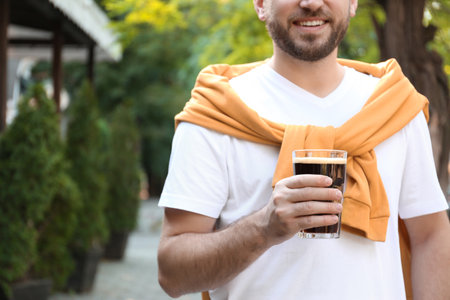 Young man with cold kvass outdoors, closeup. Traditional Russian summer drinkの写真素材