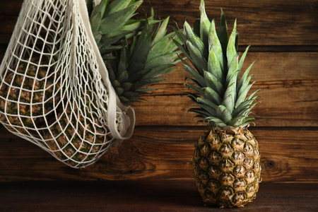 Bag and fresh juicy pineapples on wooden backgroundの写真素材