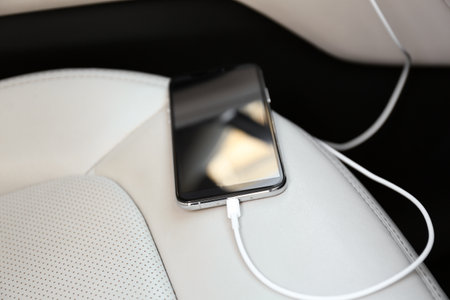 Mobile phone with charging cable in car, closeup