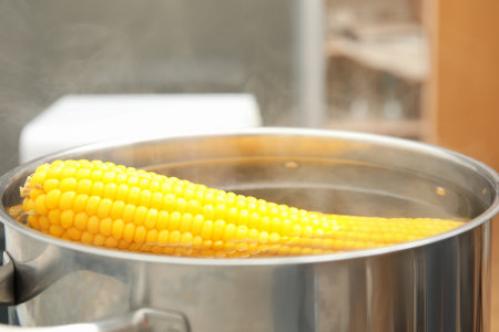 Pot with boiling corn cobs in kitchen, closeupの写真素材