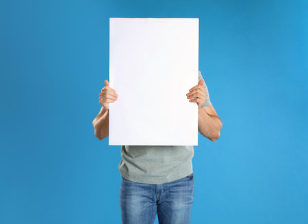 Man holding blank poster on blue backgroundの写真素材