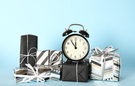 Vintage alarm clock with Christmas decor on light blue background. New Year countdown