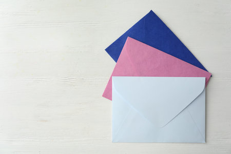 Colorful paper envelopes on white wooden table, flat lay. Space for textの写真素材