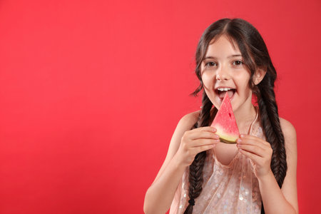 Cute little girl with watermelon on red background. Space for textの写真素材