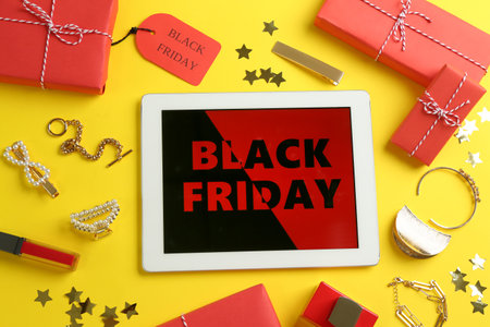 Flat lay composition with tablet, gifts and accessories on yellow background. black friday saleの写真素材