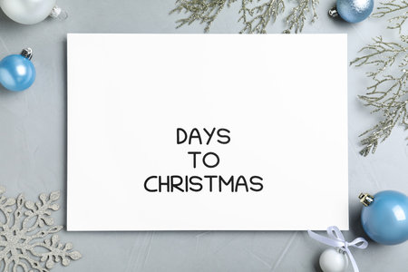 Flat lay composition of card with words Days To Christmas and space for text on light gray stone...