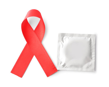 Red ribbon and condom isolated on white, top view. AIDS disease awarenessの写真素材