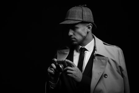 Old fashioned detective with camera on dark background, black and white effect. Space for textの写真素材