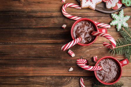 Flat lay composition with cups of hot chocolate and Christmas candy canes on wooden table. Space for textの写真素材