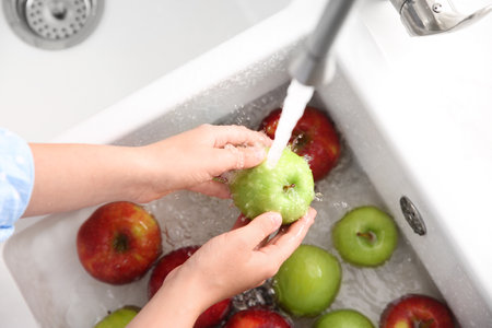 Woman washing fresh apples in kitchen sink, closeupの写真素材