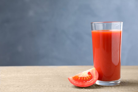 Delicious fresh juice and slice of tomato on wooden table. Space for textの写真素材