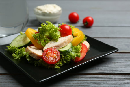 Delicious salad with chicken and vegetables on gray wooden table, closeupの写真素材