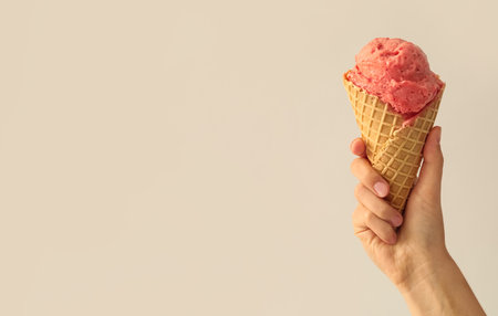 Woman holding waffle cone with delicious pink ice cream on white background, closeup. Space for textの写真素材
