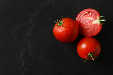 Fresh ripe tomatoes on black table, flat lay. Space for textの写真素材
