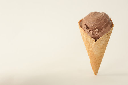 Delicious chocolate ice cream in waffle cone on white background. Space for textの写真素材