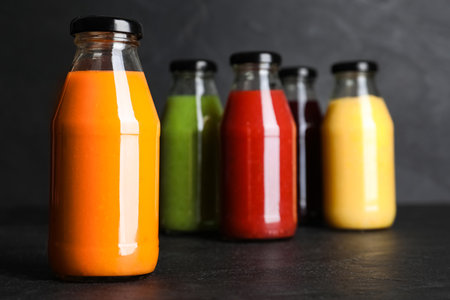Bottles with delicious colorful juices on black tableの写真素材