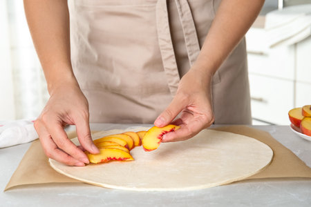 Woman making peach pie at kitchen table, closeupの写真素材