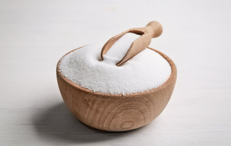 Wooden bowl with natural salt and scoop on white table, closeupの写真素材