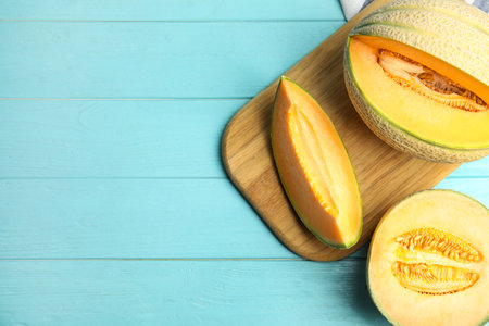 Tasty fresh melons on light blue wooden table, flat lay. Space for textの写真素材