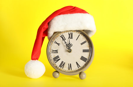 Vintage alarm clock with Christmas decor on yellow background. New Year count downの写真素材
