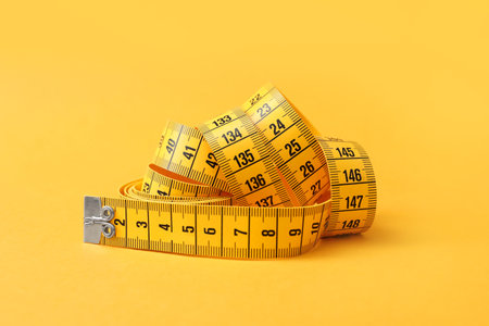 New measuring tape on orange background, closeupの写真素材