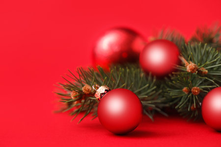Beautiful Christmas balls and fir branches on red backgroundの写真素材