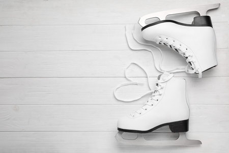 Pair of ice skates on white wooden background, top view. Space for textの写真素材
