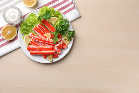 Delicious crab sticks served on wooden table, flat lay. Space for textの写真素材