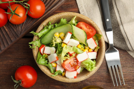 Crab stick salad with tomatoes and lettuce on wooden table, flat layの写真素材